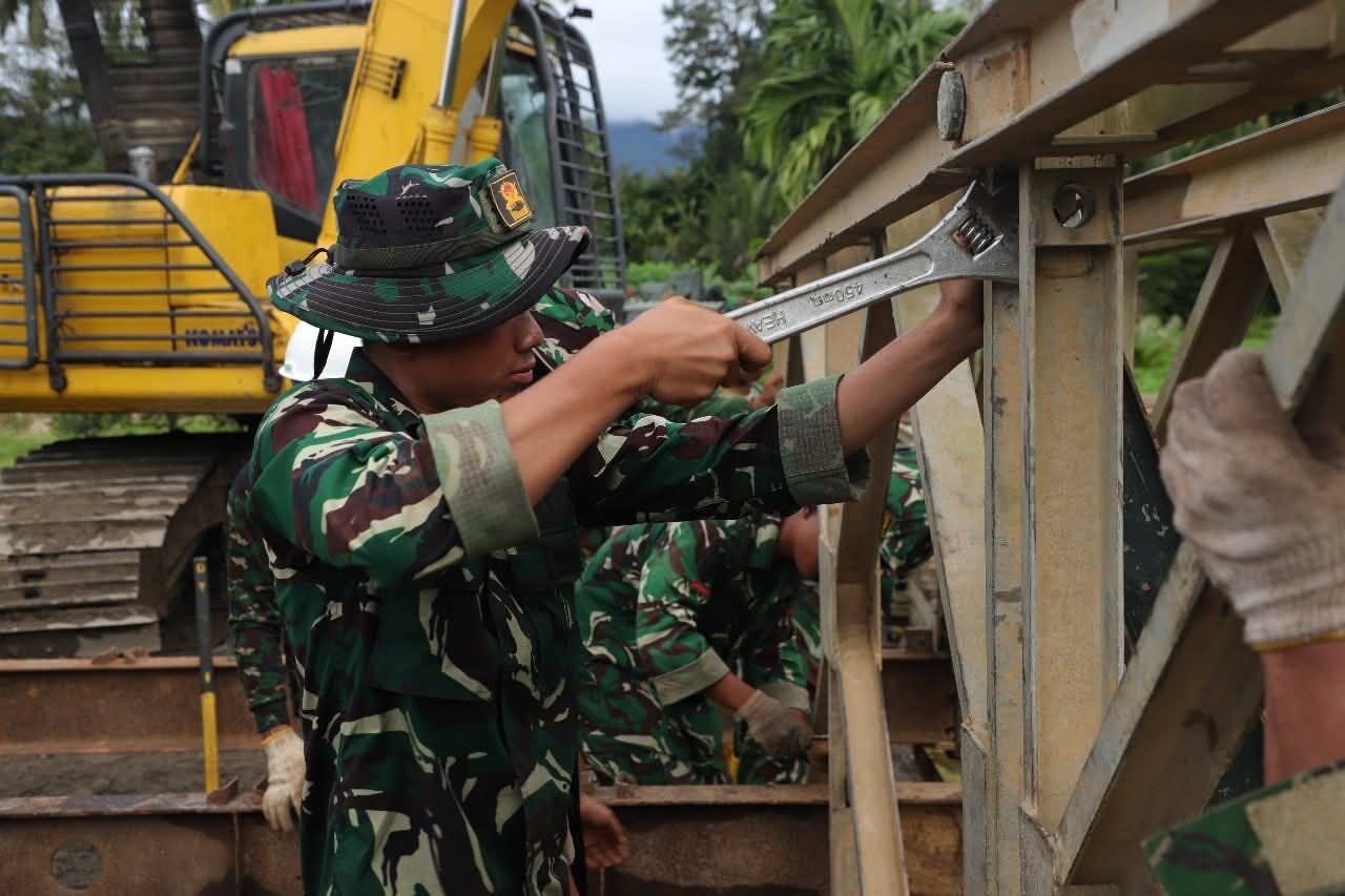 Anggota TNI terlihat sedang melakukan pengencangan baut sambungan jembatan.